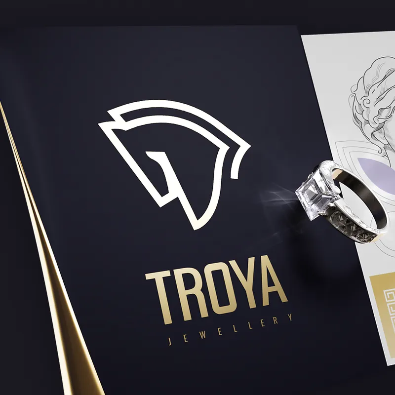 Troya horse-head logo on a dark card beside a diamond ring