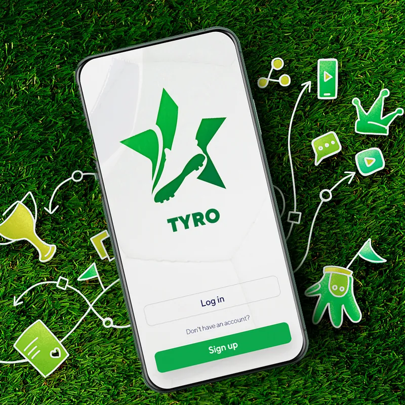 Phone showing the Tyro football app login screen lying on green grass
